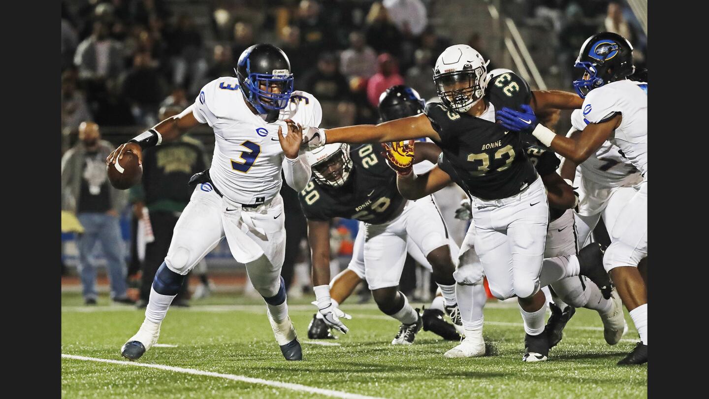 Crenshaw quarterback Isaiah Johnson (3) tries to evade the pressure from Narbonne defensive end Rooney Amisone (33) during the City Section Open Division championship game