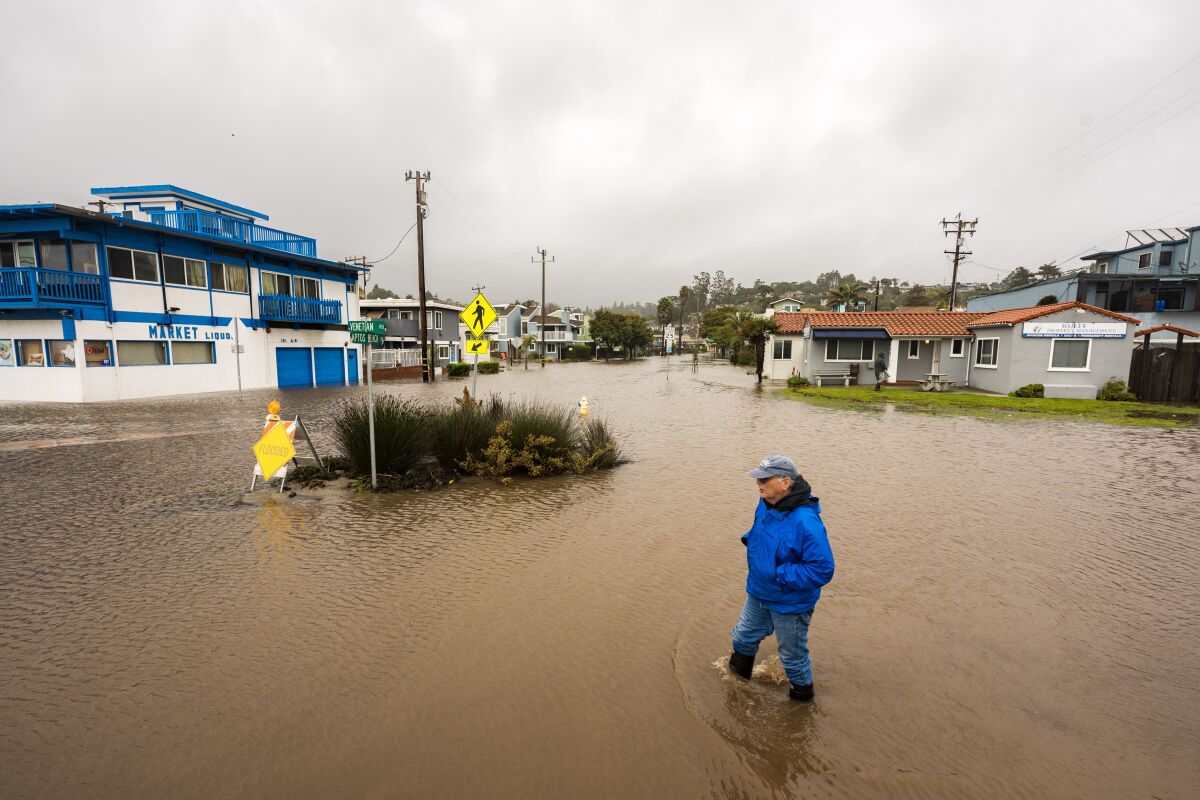 A pedestiran wades through a flooded neighborhood.