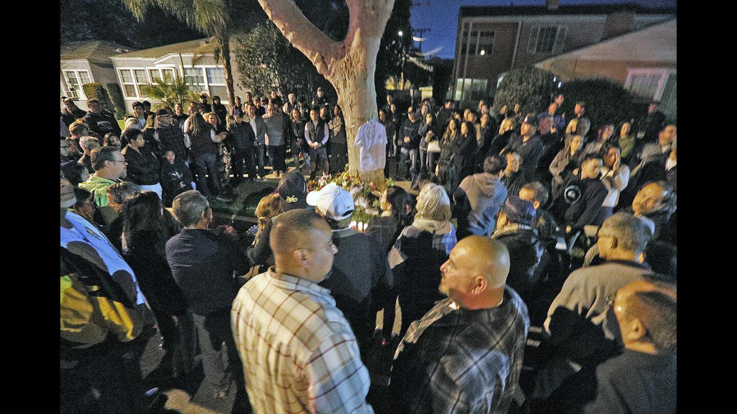 A large circle of people that spread onto the second lane of Alamada Avenue surrounds a shrine for fallen friend and bicyclist Lenny Trinh on the 1300 block of Alameda Avenue in Burbank on Wednesday, April 18, 2018. This is the location where Lenny Trinh was killed on his bicycle earlier in the week. Over 100 people, mostly family and friends with some who paid tribute but didn't know him, told stories, and chained a "ghost bike" to a tree.