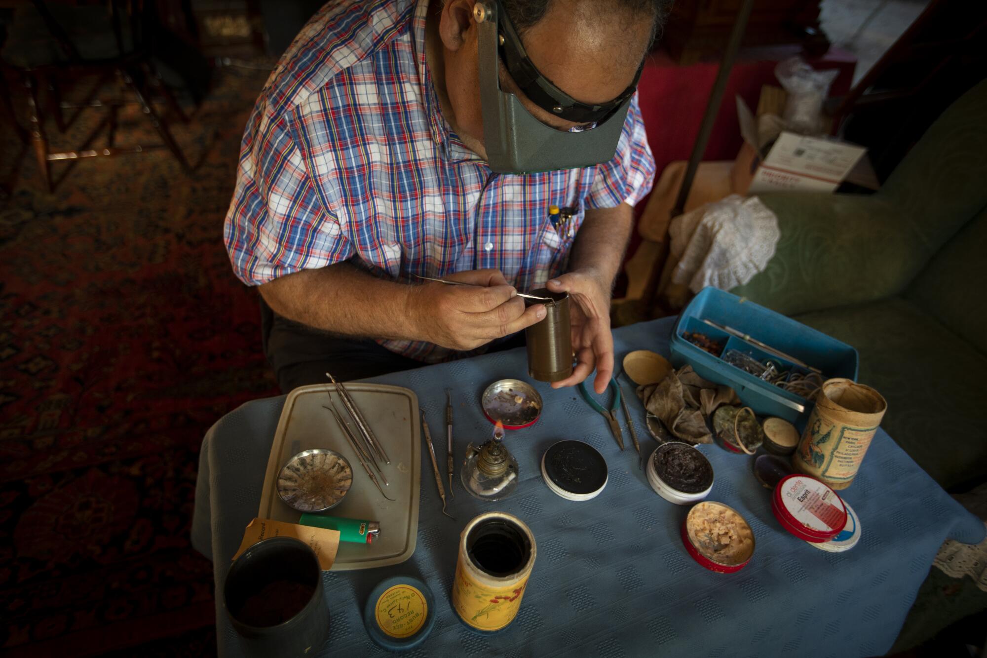 Collector Michael Khanchalian repairs a wax cylinder using dental instruments.