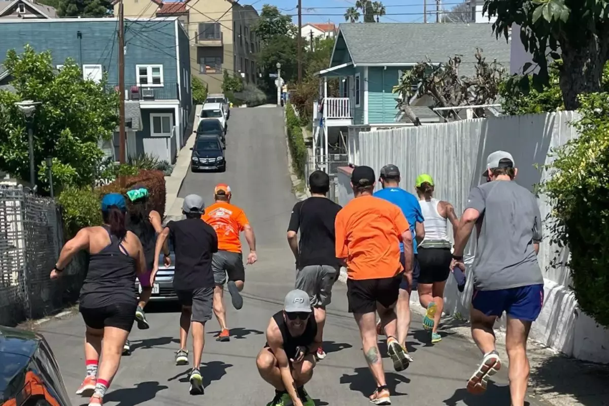 A group of runners seen from behind on a narrow residential street.