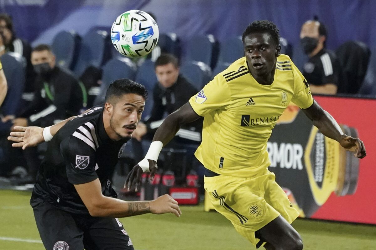 Nashville SC attacker Dominique Badji, right, and Inter Miami defender Nicolas Figal chase after the ball.