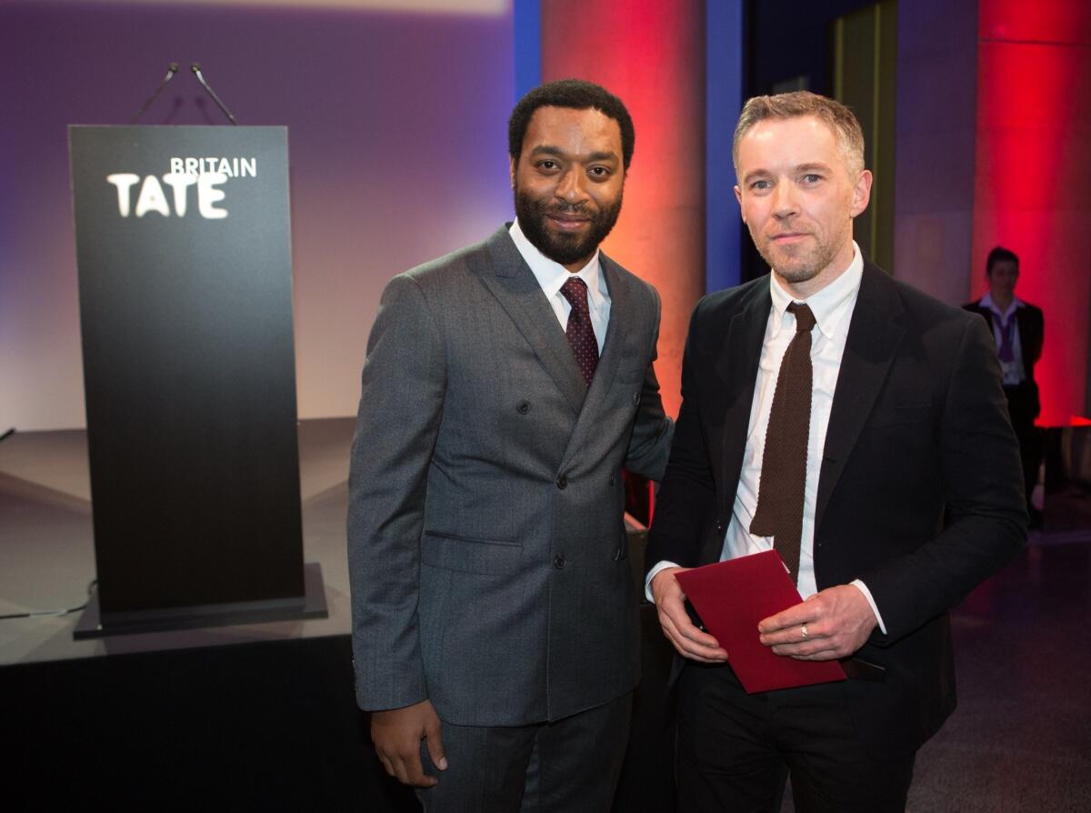 British actor Chiwetel Ejiofor, left, presents Irish-born artist Duncan Campbell with this year's Turner Prize for "It for Others," at the Tate Britain in central London on Monday.