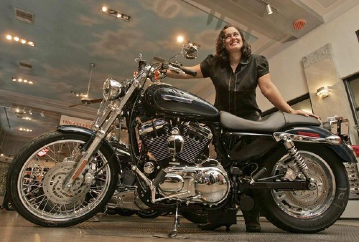 Emily Vindeni, controller of the Harley-Davidson shop in Glendale, poses with a Sportster, Harley's smallest, least expensive bike. Sales are slow for the costly touring models but Sportster demand is healthy.