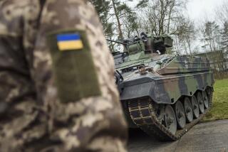 FILE - A Ukrainian soldier is standing in front of a Marder infantry fighting vehicle at the German forces Bundeswehr training area in Munster, Germany, on Feb. 20, 2023. Germany's aid for Ukraine will be “massively expanded” next year, the foreign minister said Monday, Nov. 13, 2023 as Kyiv heads into its second winter since Russia launched its full-scale invasion. Germany has become one of Ukraine's top military suppliers since the war started in February 2022, sending material that includes tanks, armored personnel carriers, air defense systems and Patriot missile systems. (AP Photo/Gregor Fischer, File)