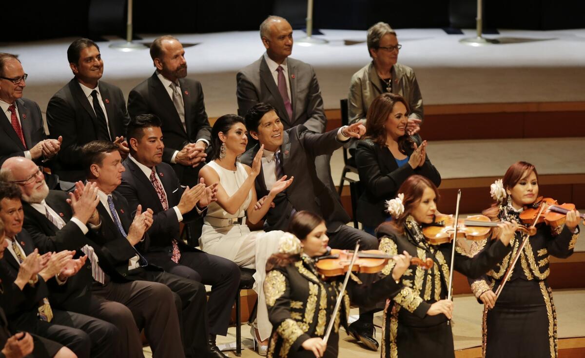 As the Mariachi Divas play, Kevin de León, with his daughter Lluvia Carrasco, points to friends in the crowd at his swearing-in ceremony.