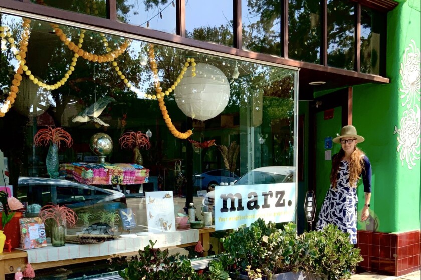 A woman in a hat stands in the doorway of a shop.