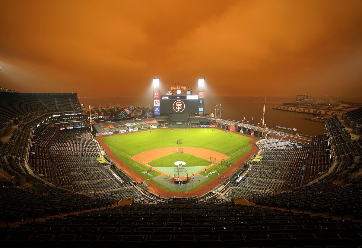 Smoke from California wildfires obscures the sky over Oracle Park as the Seattle Mariners take batting practice before their baseball game against the San Francisco Giants on Wednesday, Sept. 9, 2020, in San Francisco. People from San Francisco to Seattle woke Wednesday to hazy clouds of smoke lingering in the air, darkening the sky to an eerie orange glow that kept street lights illuminated into midday, all thanks to dozens of wildfires throughout the West. (AP Photo/Tony Avelar)