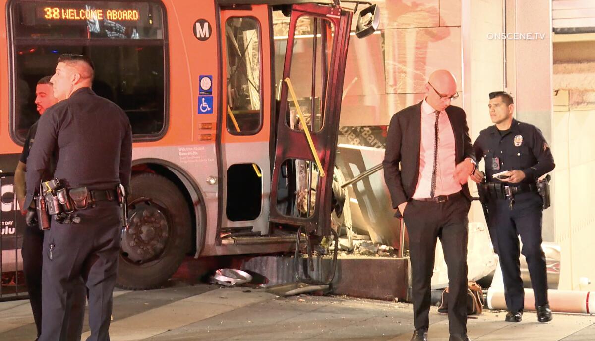 Passengers and police stand outside a crashed bus.