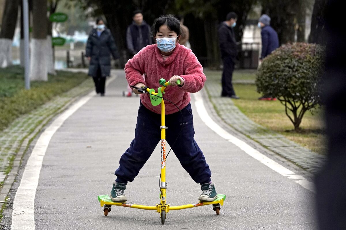 A child wearing a mask rides on a skate scooter in Wuhan.