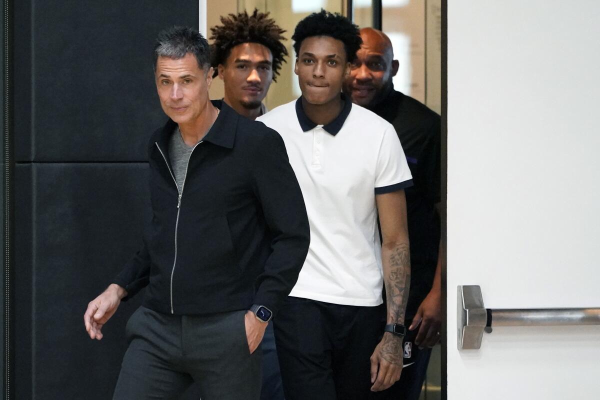 Lakers GM Rob Pelinka, left, walks with coach Darvin Ham, right, and draft picks Jalen Hood-Schifino and Maxwell Lewis.