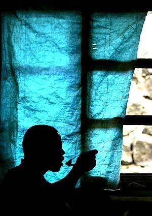 A former soldier eats lunch in his bedroom that he shares with eight other children at a transit center in Goma, Congo.