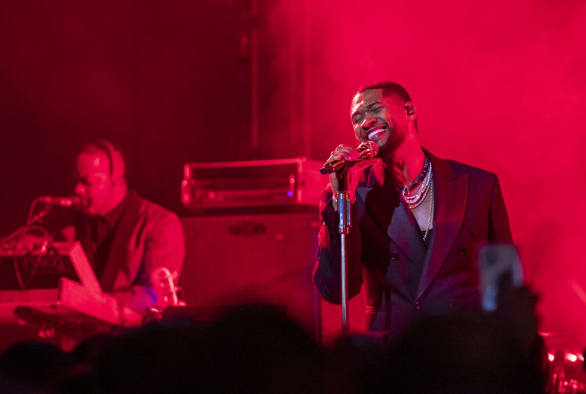 Usher bathed in red light on a stage.