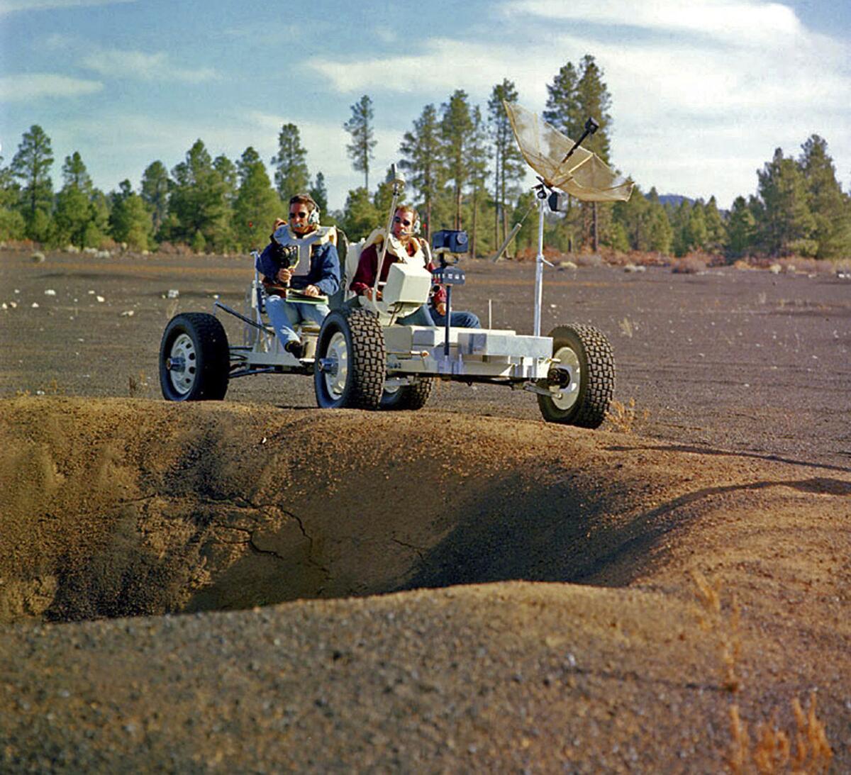Apollo 15 astronauts Jim Irwin, left, and David Scott drive a prototype of a lunar rover in a volcanic cinder field east of Flagstaff, Ariz. Geology lessons were an important part of the Apollo astronauts' training.