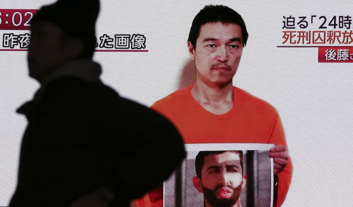 Japanese hostage Kenji Goto holds what appears to be a photo of Jordanian pilot Lt. Moaz Kasasbeh in a YouTube video projected on a big screen TV on Wednesday. The Islamic State hostage has reportedly been beheaded by his captors.