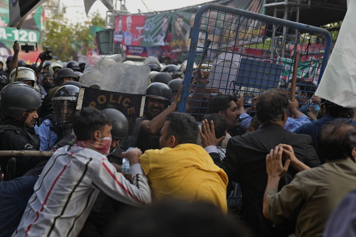 Supporters of former Prime Ministry Imran Khan's party scuffle with riot police officers outside Khan's residence, in Lahore, Pakistan, Tuesday, March 14, 2023. Pakistani police scuffled with supporters of former Prime Minister Imran Khan as officers arrived outside his home to arrest him for failing to appear in court on graft charges, police and officials said. (AP Photo/K.M. Chaudary)