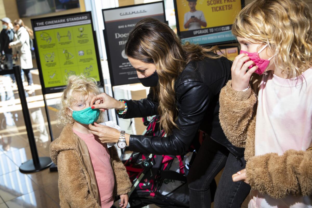 A woman adjusts her children's masks.