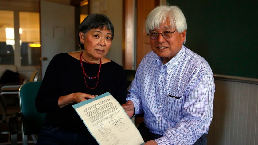 Ann Tsuchiya and Larry Oda hold the 1945 petition with signatures of Monterey citizens including John Steinbeck welcoming Japanese internees back.