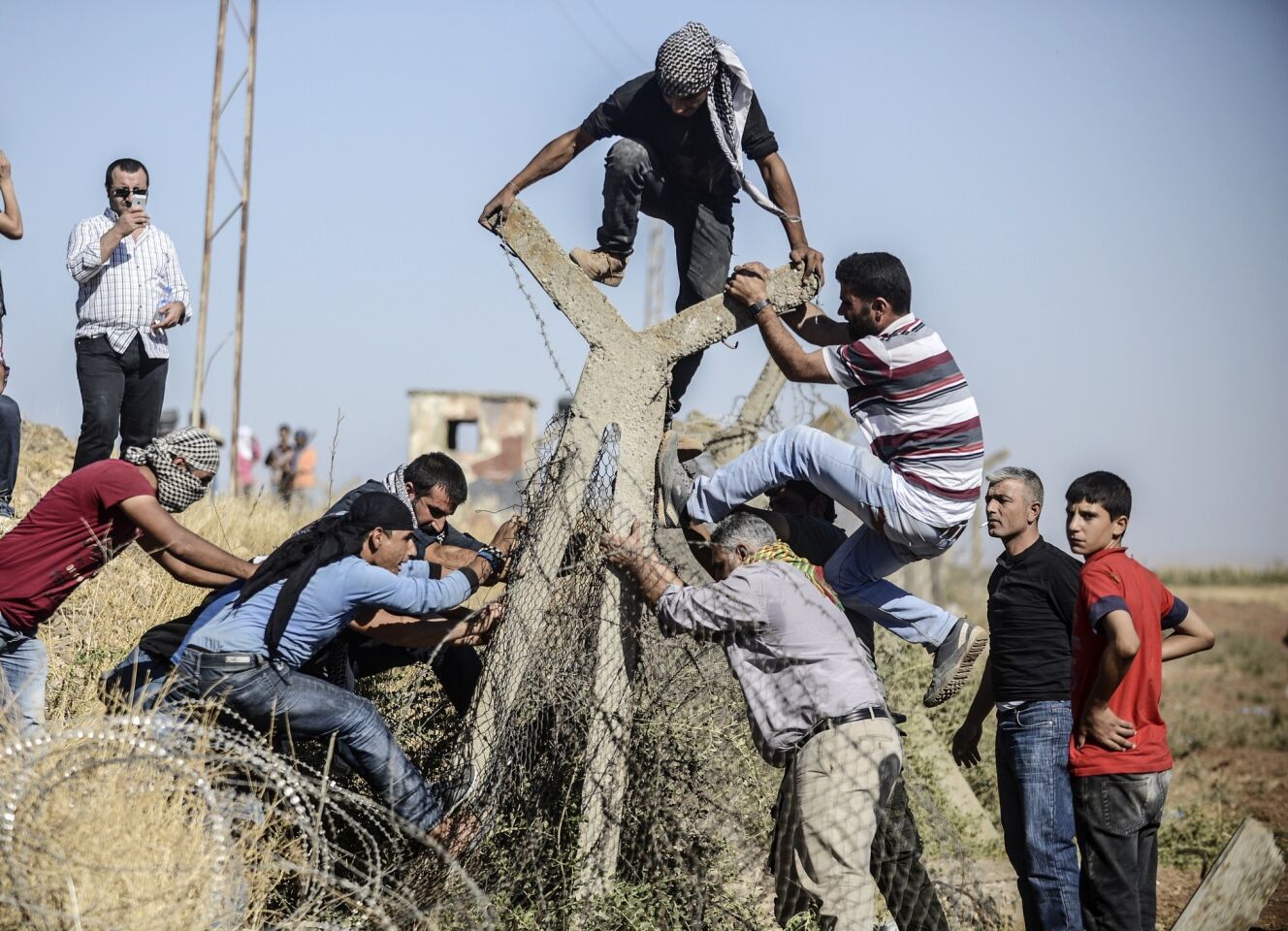Turkish and Syrian Kurds try to tear down a border fence during protests against the extremist group Islamic State on Sept. 16. Refugees fleeing the militants have flooded into Turkey from Syria.