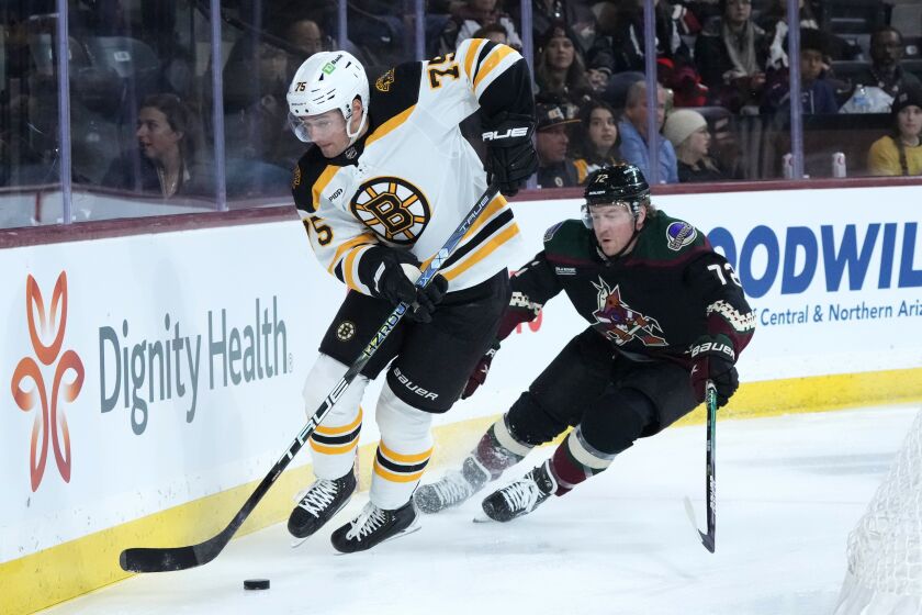 Boston Bruins defenseman Connor Clifton (75) skates with the puck against Arizona Coyotes center Travis Boyd (72) during the first period of an NHL hockey game in Tempe, Ariz., Friday, Dec. 9, 2022. (AP Photo/Ross D. Franklin)