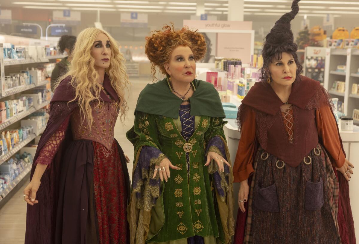 Three witches stand in the middle of a drugstore.