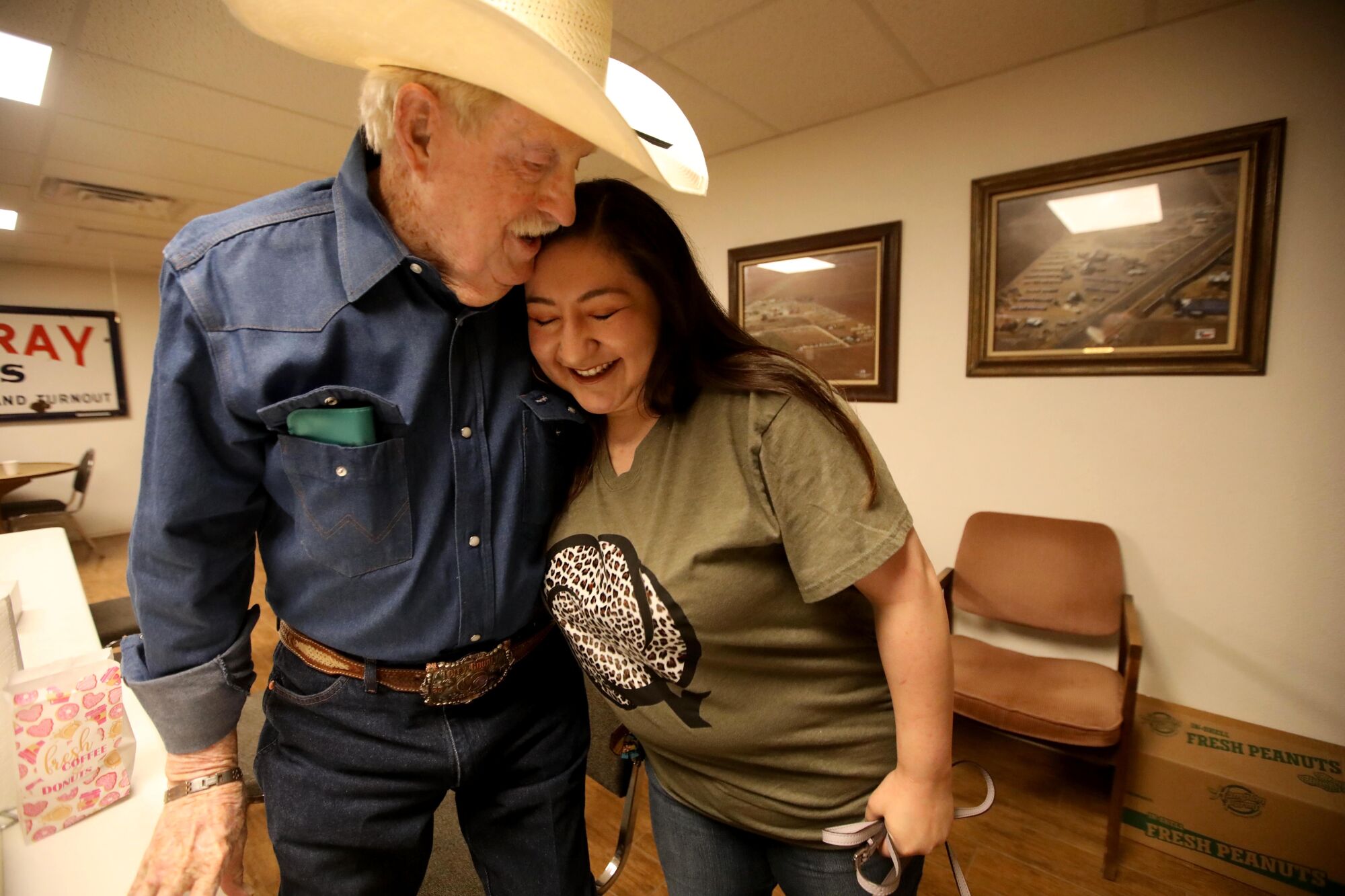 Ray Gober, 87, hugs Reagan Perez at Meadow Farmers Co-op, a local cotton gin in Meadow, Texas.