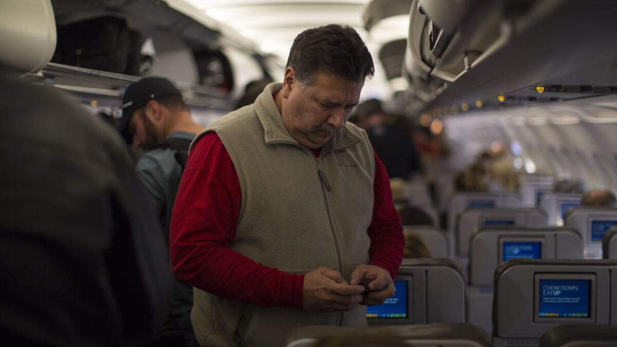 A JetBlue passenger checks his cellphone before disembarking at Long Beach Airport. (Robert Nickelsberg / Getty Images)