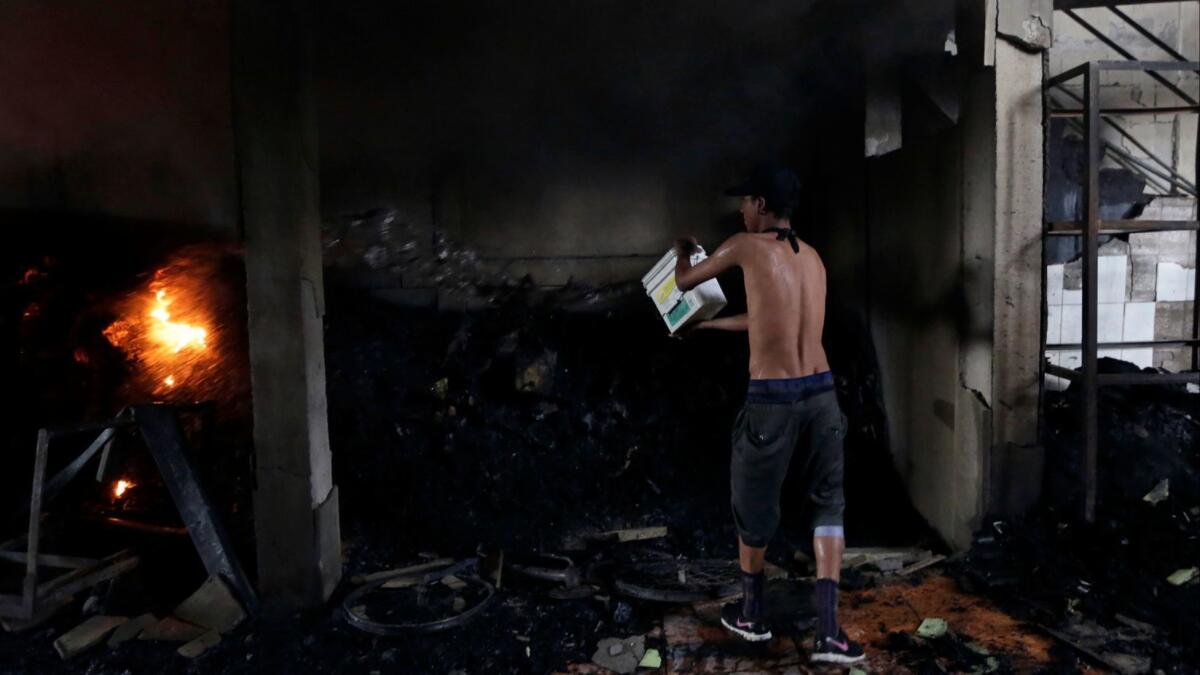 A man works to extinguish what remains of an arson house fire that killed four adults and two children in Managua on Saturday.