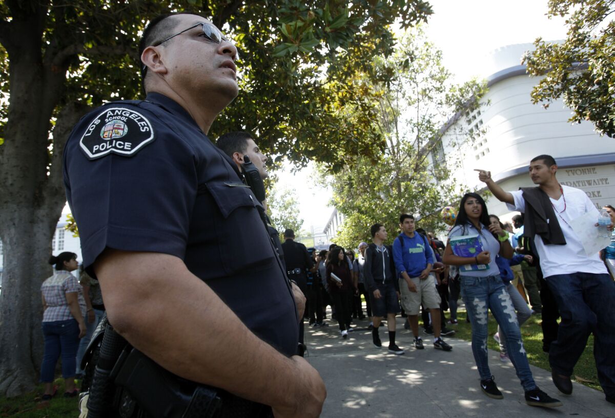 LAUSD police officer Jay Cueva watches as students get out of Manual Arts High School. 