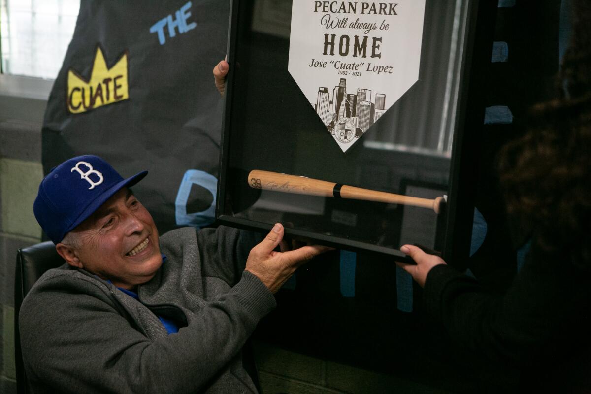 Jose "Cuate" Lopez receives a plaque with a small baseball bat