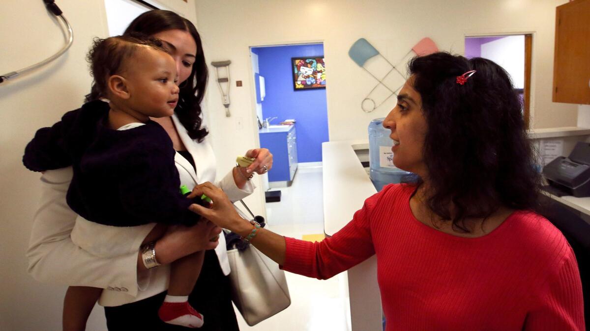 Dr. Monica Asnani says goodbye to Kristian Richard, being held by his mother, Natasha, after he was given a measles shot in Los Angeles in 2015.