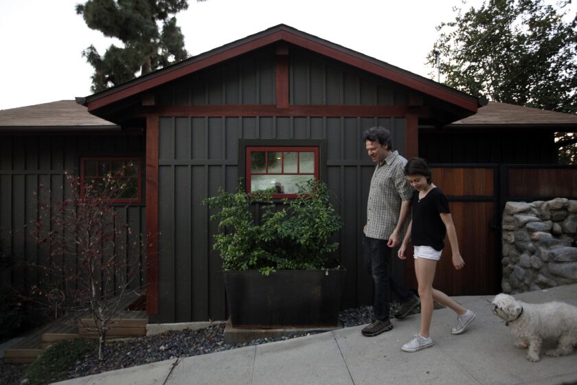 Todd Segal and his 14-year-old daughter Jay walk their dog Bubbers down the street in front of their home in Highland Park. The home's exterior siding and colors are reminiscent of New England, where Segal grew up.