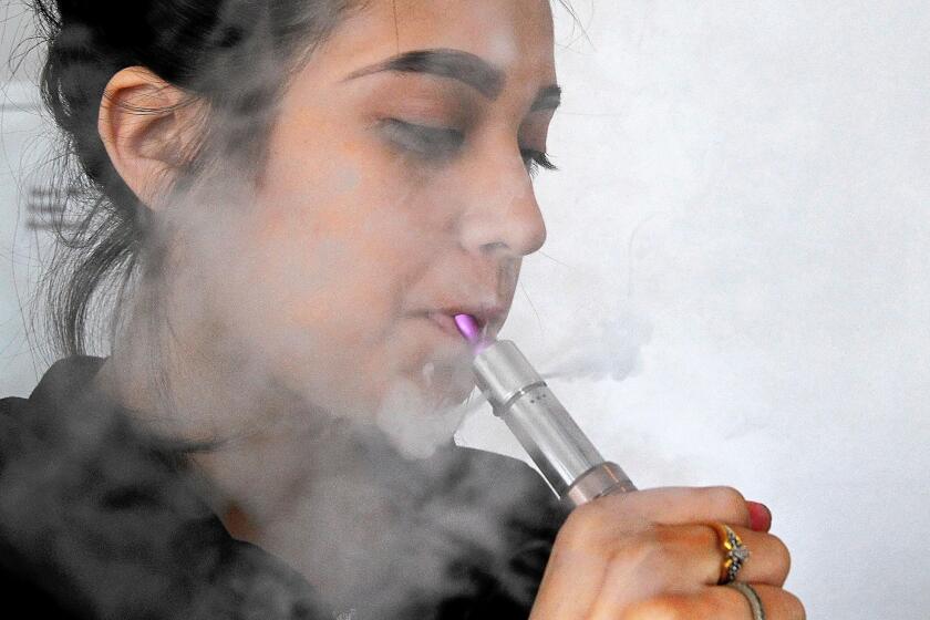 Maria Valencia uses an electronic cigarette to vaporize a nicotine soultion at Vaping Ape, an e-cigarette retailer in Hollywood. E-cigarette companies are preying on young consumers by using candy flavors, social media ads and free samples at rock concerts, according to a report released Monday by Democratic lawmakers.