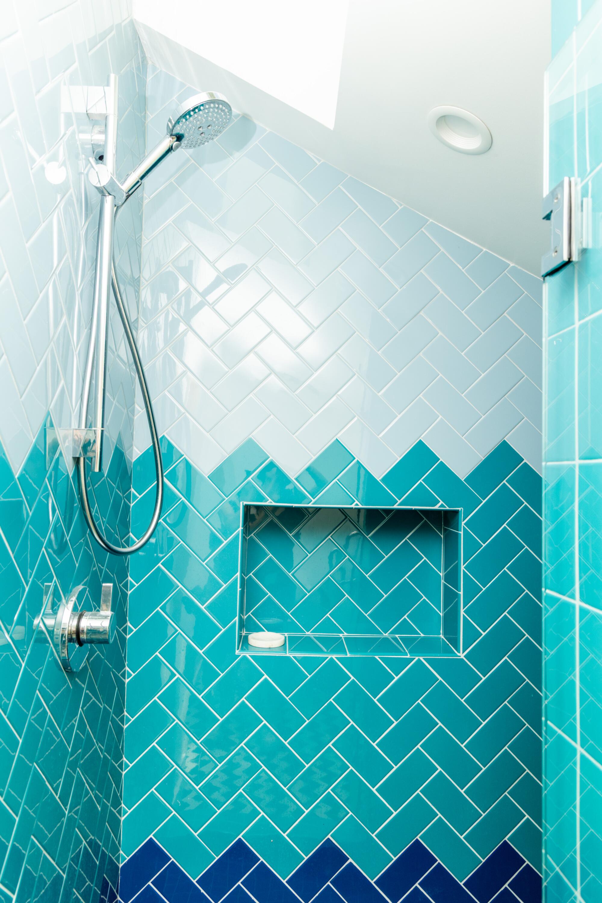Tile in various shades of blue in a shower with a high ceiling.