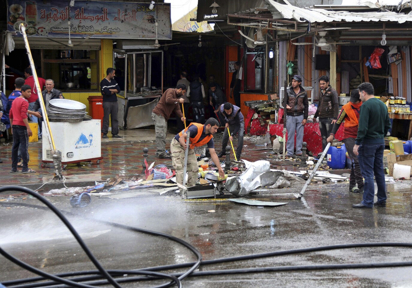 Iraqis clean the streets after a suicide bombing in New Baghdad. It was the deadliest of three bombings Saturday.