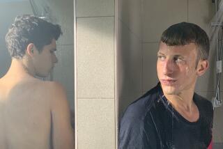 Two young men, one clothed, shower in adjoining stalls in the movie "The Swimmer."