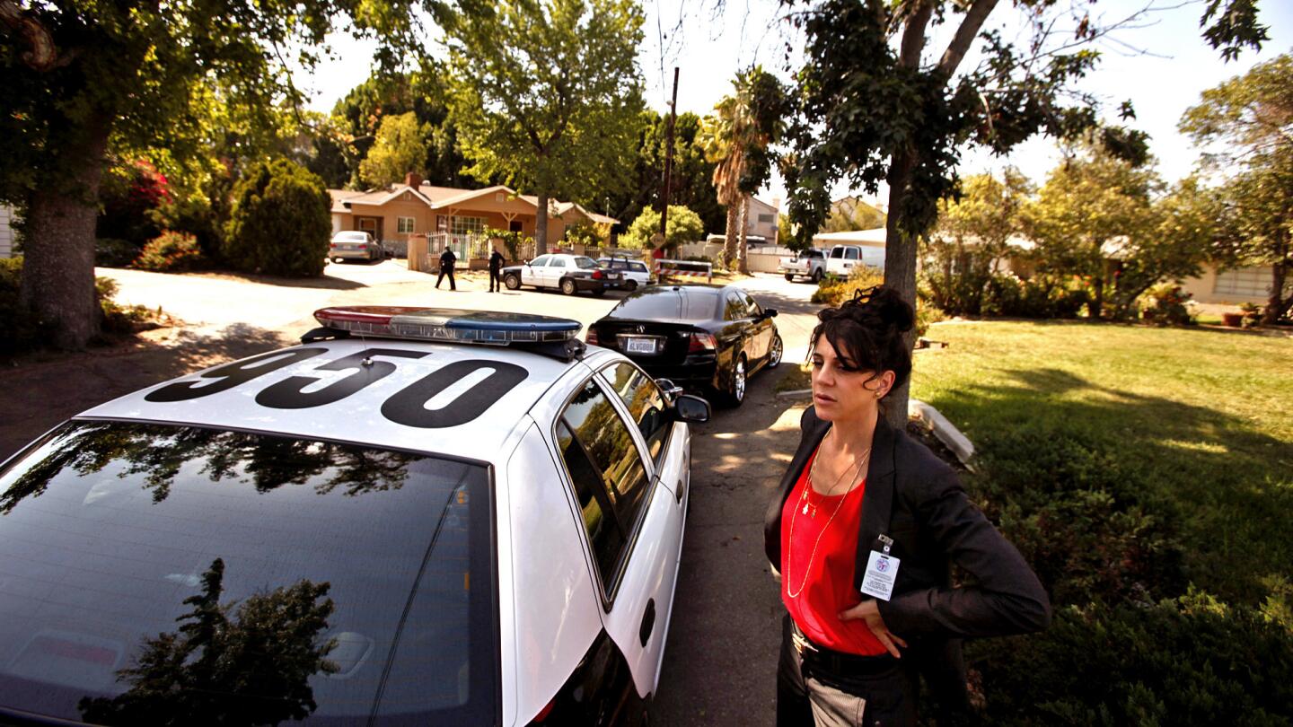 Deputy City Atty. Ayelet Feiman, with the Neighborhood Prosecutor Program, stands next to a police car while officers wait to talk with a problem homeowner in Panorama City.