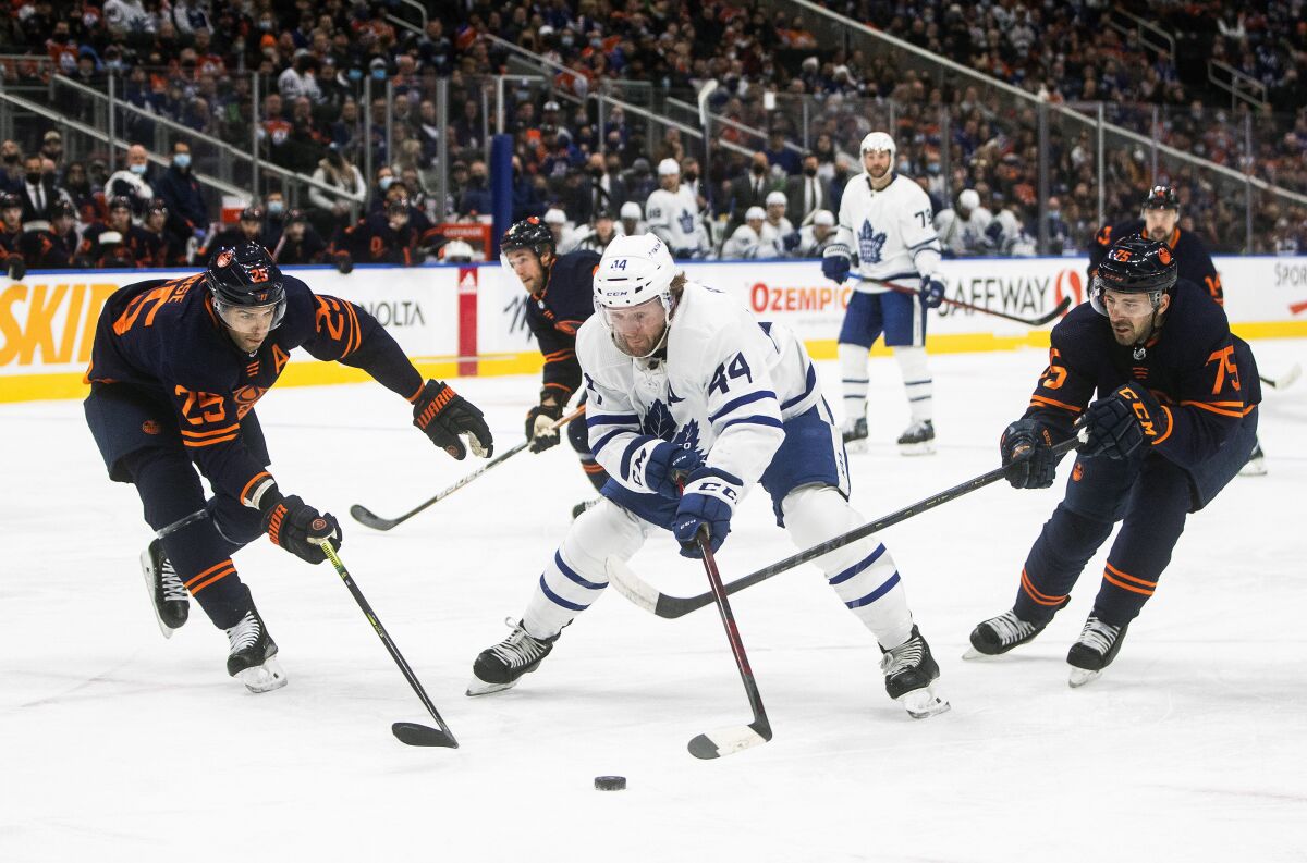 Toronto Maple Leafs' Morgan Rielly (44) is chased by Edmonton Oilers' Darnell Nurse (25) and Evan Bouchard (75) during the first period of an NHL hockey game Tuesday, Dec. 14, 2021 in Edmonton, Alberta (Jason Franson/The Canadian Press via AP)