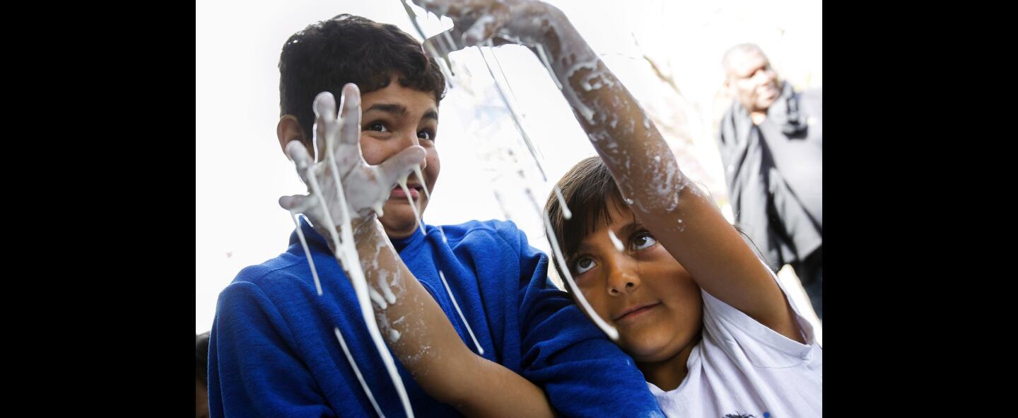 As her brother Marcus Roman, 12, watches, Judy Roman, 7, lets "Oobleck", a mix of corn starch and water, drip from her hands while at the Association for Women in Science booth.