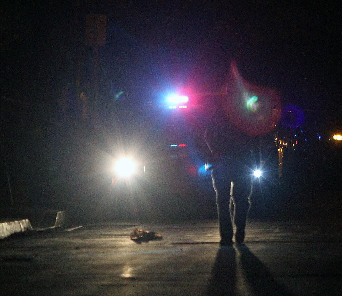 A Burbank police officer walks by the shirt of a victim at a shooting scene on Naomi Street and Thornton Avenue, near Robert E. Lundigan Park, in Burbank on Thursday, Feb. 4, 2016.