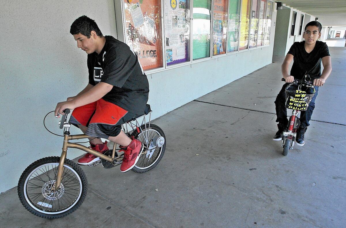 Sarkis Agazarian, 14, left, rides a electric powered BMX bike created by students at Luther Burbank Middle School while Arthur Ayanian, 14, rides a previous project, an electric scooter on Monday, June 9, 2014.