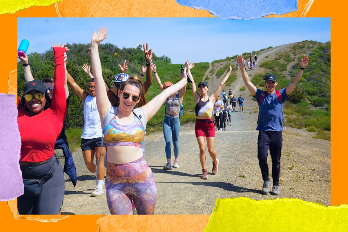 People wearing workout gear smile and hold up their hands on a trail.