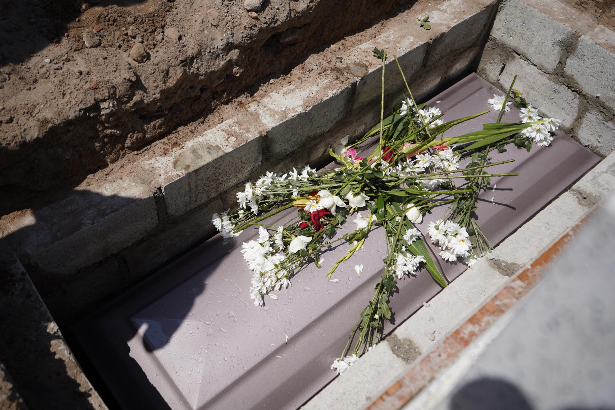 Family members toss flowers into the grave of Maria Eugenia Chavez Segovia.