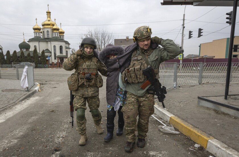Ukrainian servicemen help an elderly woman, in the town of Irpin, Ukraine, Sunday, March 6, 2022. (AP Photo/Andriy Dubchak)