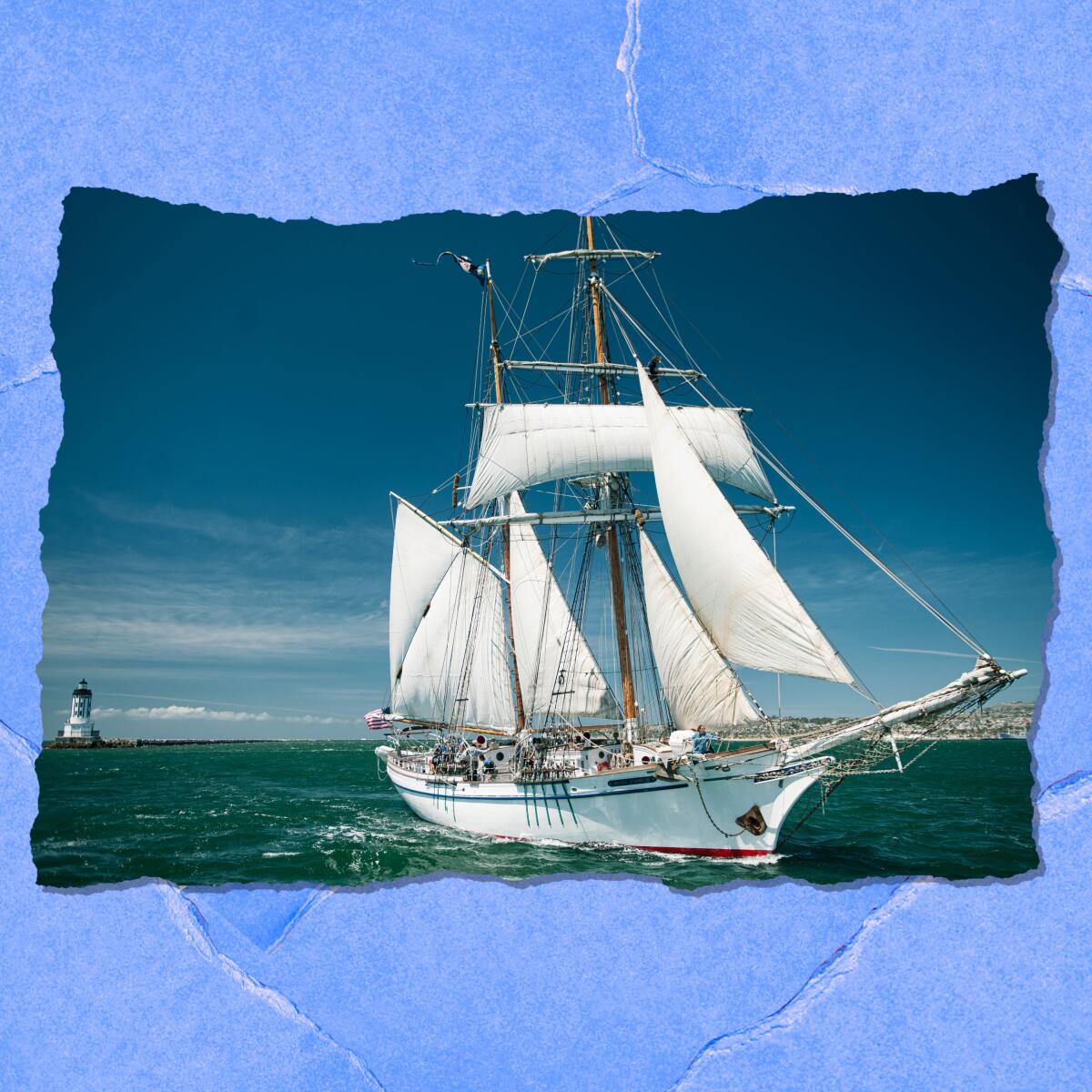 A tall ship floats offshore on a clear day. In the background is a lighthouse.