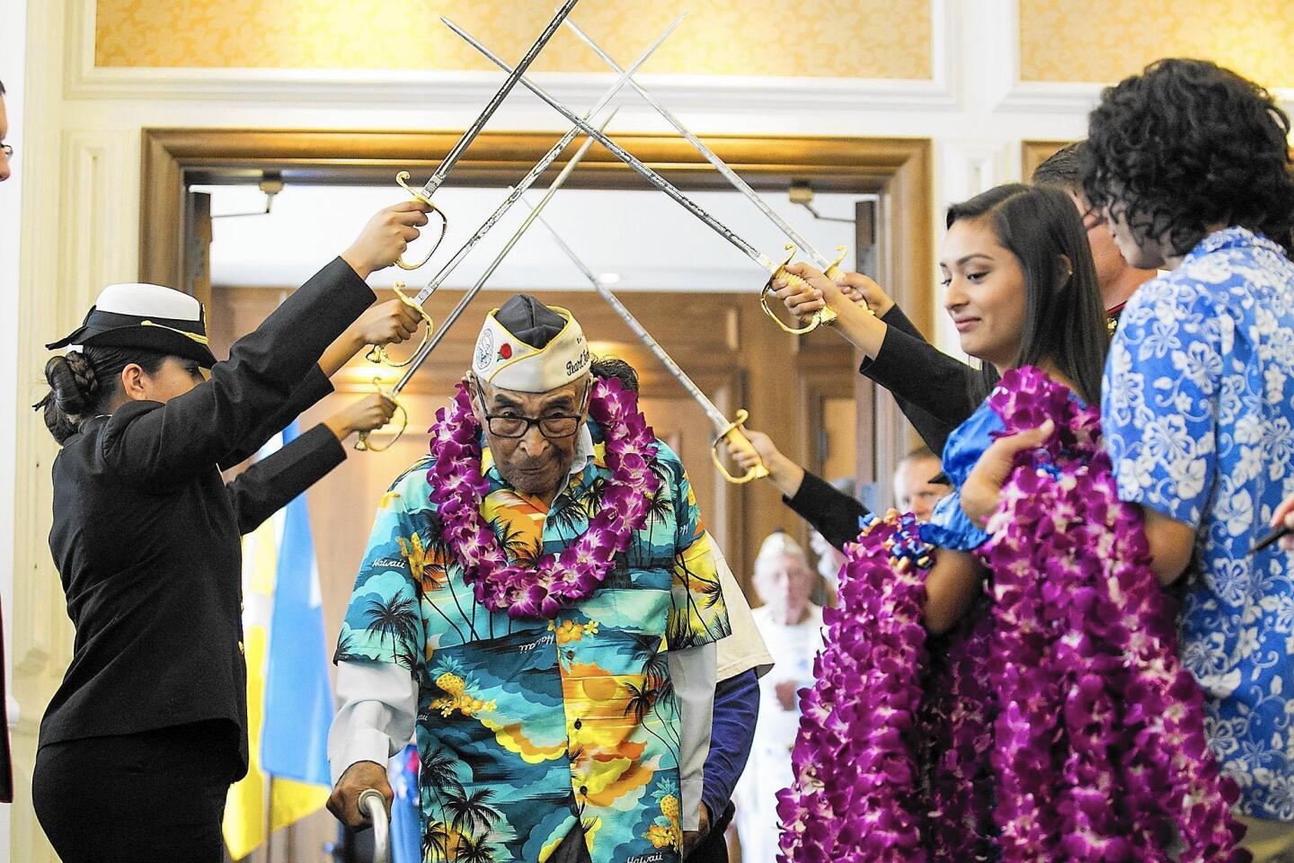 Raymond Chavez enters under an arch of swords held by the Santa Ana High School Navy JROTC during a luncheon to honor Pearl Harbor survivors at the Pacific Club in Newport Beach on Wednesday.