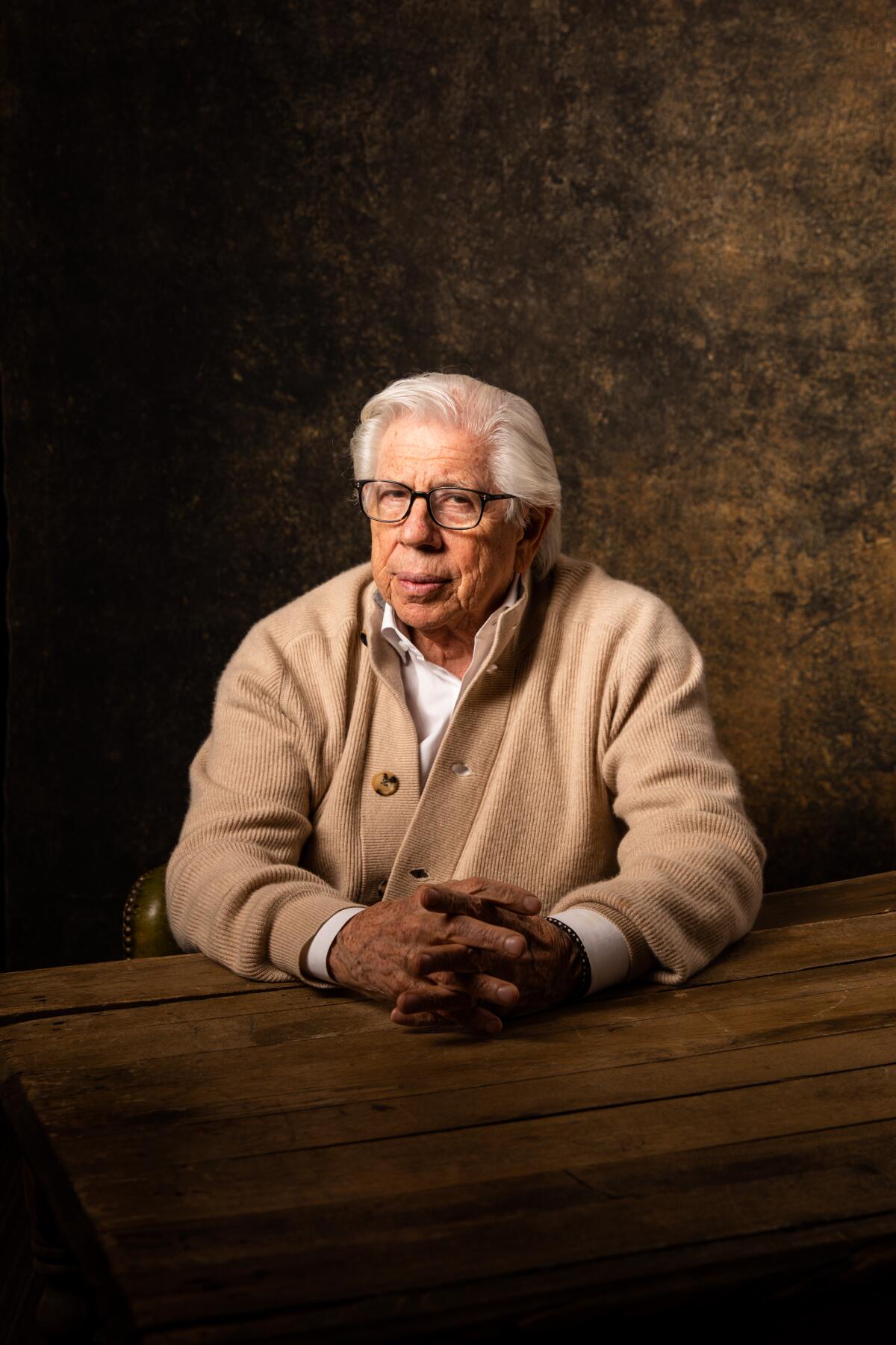 Carl Bernstein sits for a portrait with folded hands.