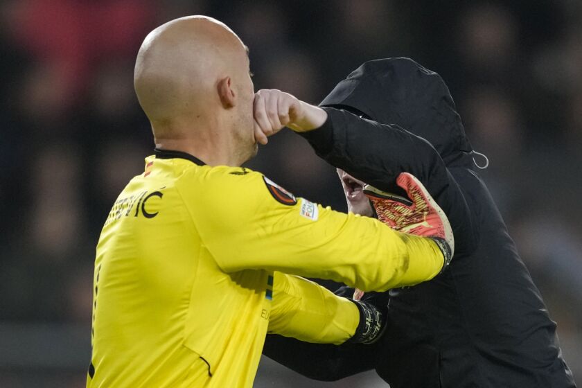 A PSV supporter punches Sevilla's goalkeeper Marko Dmitrovic in the face during the Europa League playoff second leg soccer match between PSV and Sevilla at the Philips stadium in Eindhoven, Netherlands, Thursday, Feb. 23, 2023. Sevilla won 3-2 on aggregate. (AP Photo/Peter Dejong)