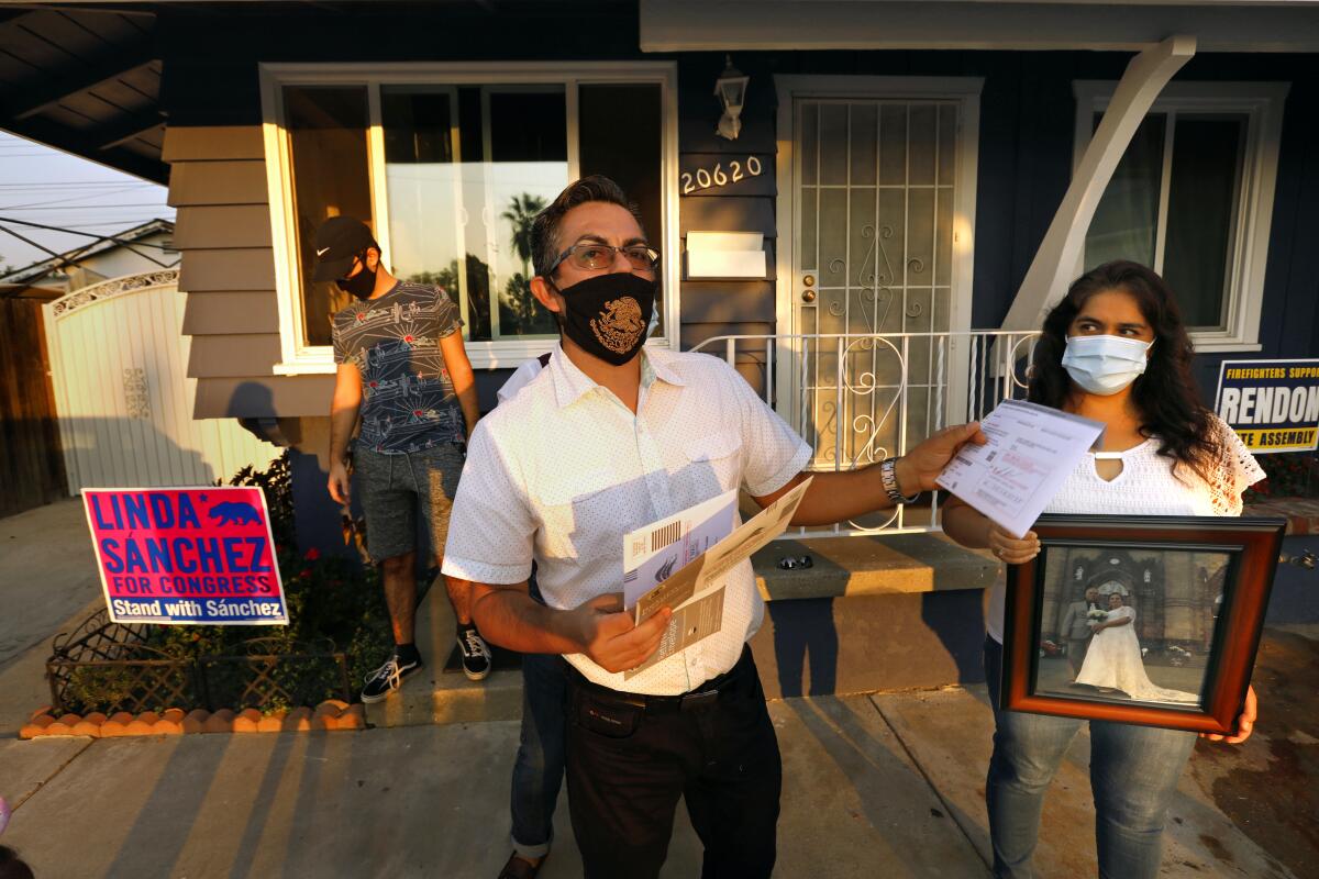 A family, all wearing masks, in front of a house