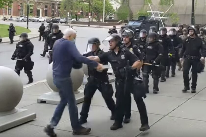 In this image from video provided by WBFO, a Buffalo police officer appears to shove a man who walked up to police Thursday, June 4, 2020, in Buffalo, N.Y. Video from WBFO shows the man appearing to hit his head on the pavement, with blood leaking out as officers walk past to clear Niagara Square. Buffalo police initially said in a statement that a person “was injured when he tripped & fell,” WIVB-TV reported, but Capt. Jeff Rinaldo later told the TV station that an internal affairs investigation was opened. Police Commissioner Byron Lockwood suspended two officers late Thursday, the mayor’s statement said. (Mike Desmond/WBFO via AP)